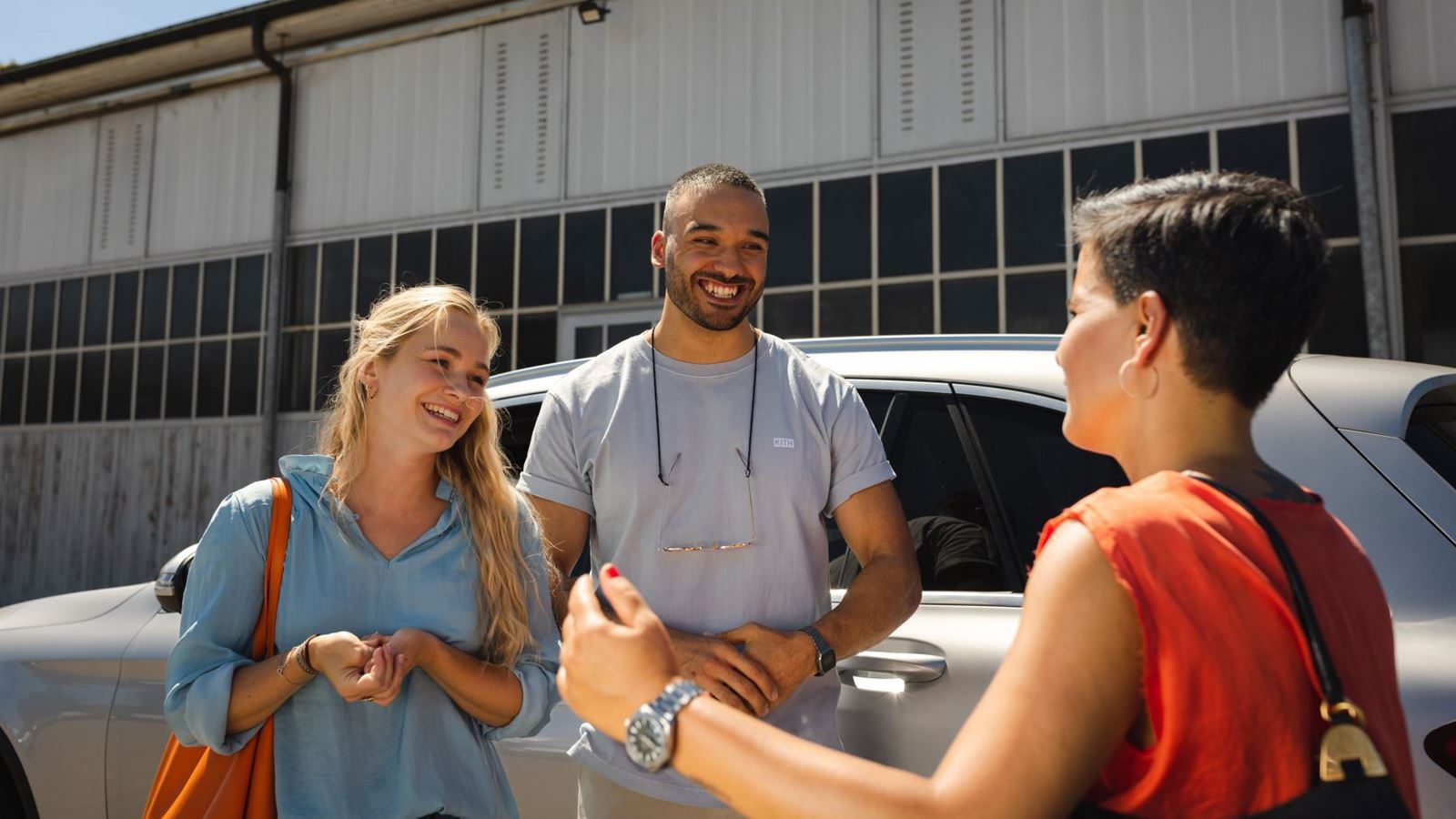 Three people meet in front of a car to commute together to their workplace.
