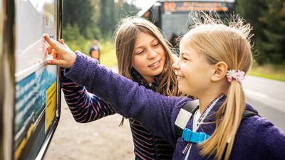 Due bambini osservano l’orario a una fermata dell’autopostale.