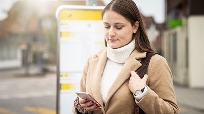 Una donna consulta il cellulare alla fermata AutoPostale.