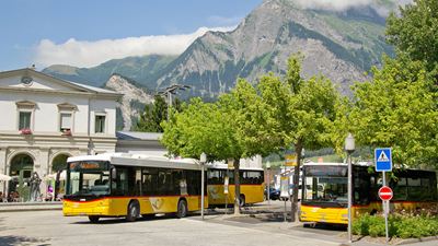 La gare de Bad Ragaz en été avec trois cars postaux, tous prêts à partir prochainement.