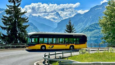 Un car postal électrique dans un virage avec vue panoramique sur les montagnes en arrière-plan