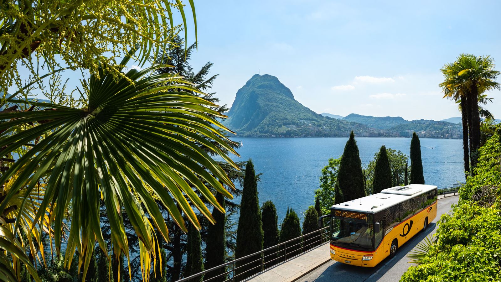 A Postbus travelling along Lake Lugano towards St Moritz, with Monte Brè in the background.