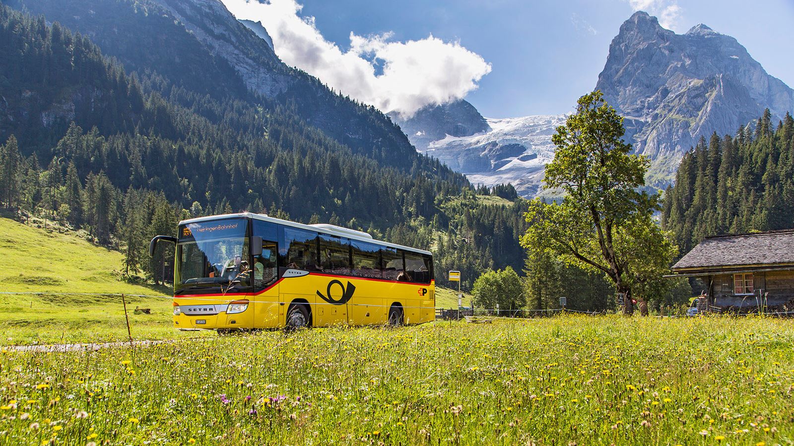 Postauto auf der Rosenlaui-Linie mit Gletscher und Wetterhorn im Hintergrund.