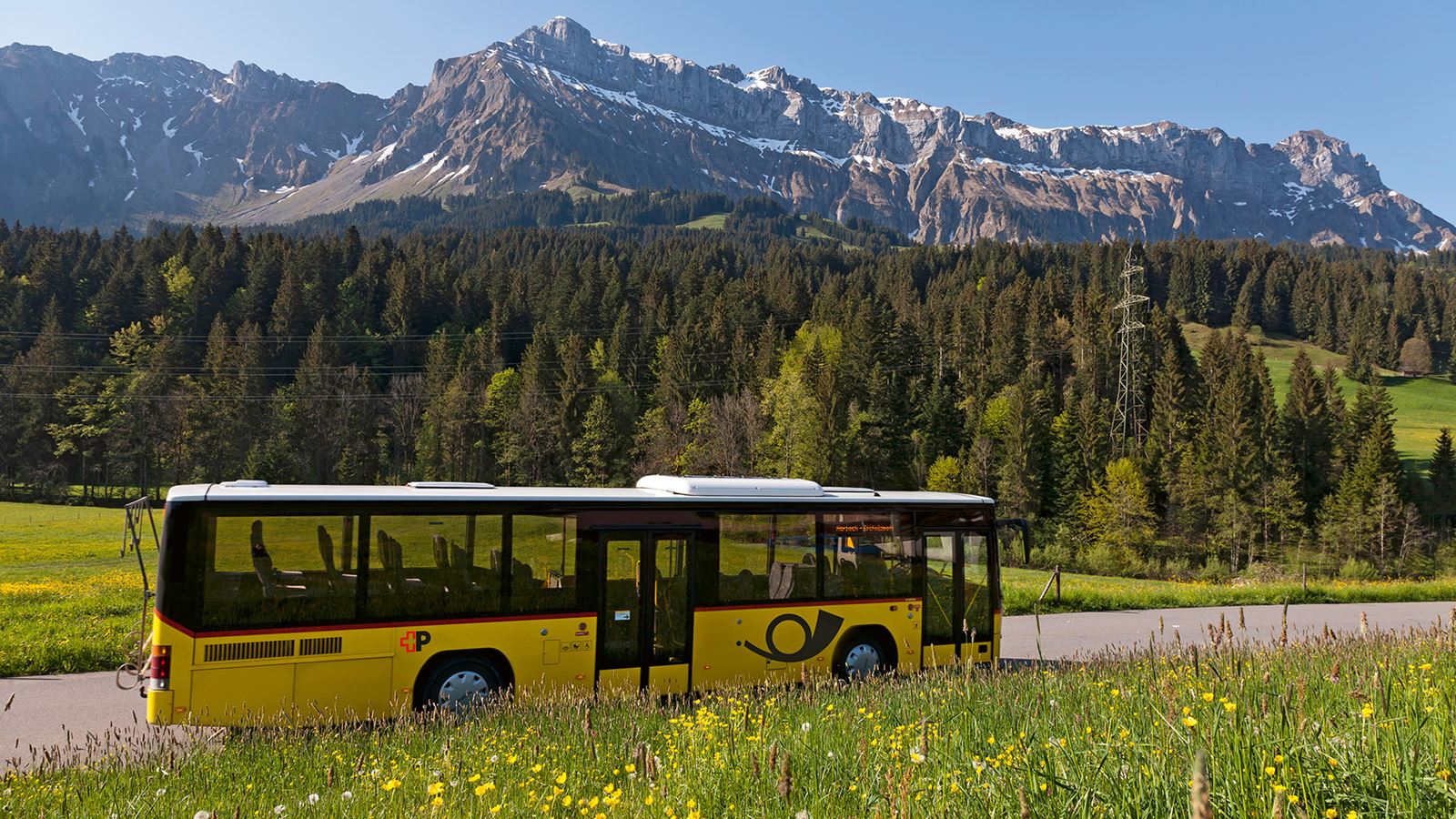 A Postbus against a mountain backdrop