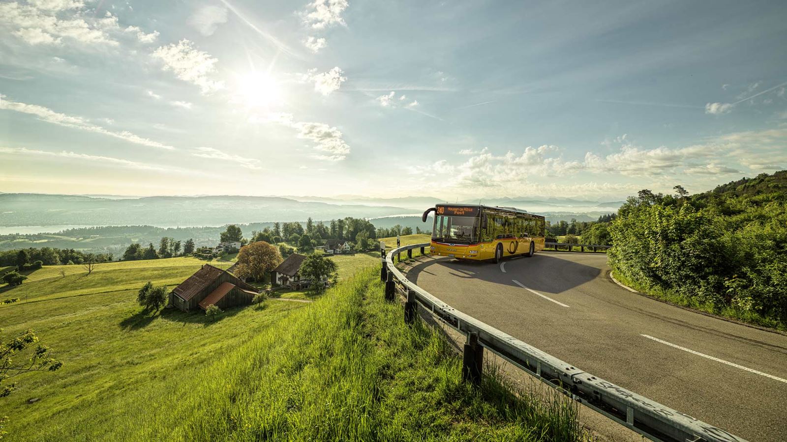 Das Postauto fährt auf der Albispassstrasse mit Blick auf den Zürichsee.