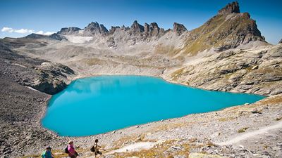 Des randonneurs passent le long du lac aux eaux bleu ciel