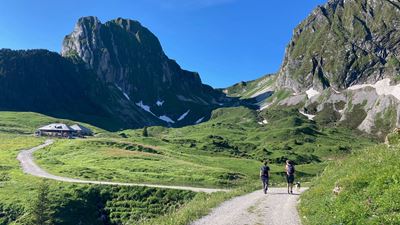 Two people with a dog on the hiking trail towards Alp Obernünenen