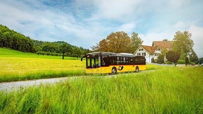 A Postbus on the road in the summer, rural ZVV region