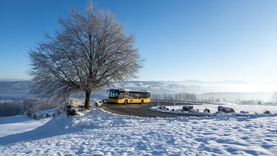 A Postbus travels over the Albis Pass in winter.