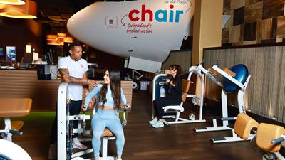 Cockpit d’avion et personnes s’entraînant dans la salle de fitness de l’Airport Fitness & Wellness de l’aéroport de Zurich.