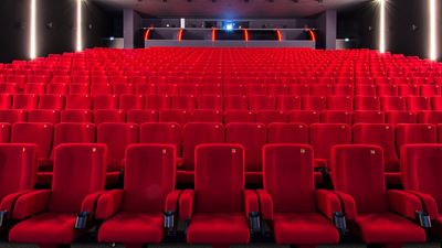 Salle de cinéma vide avec des chaises rouges.