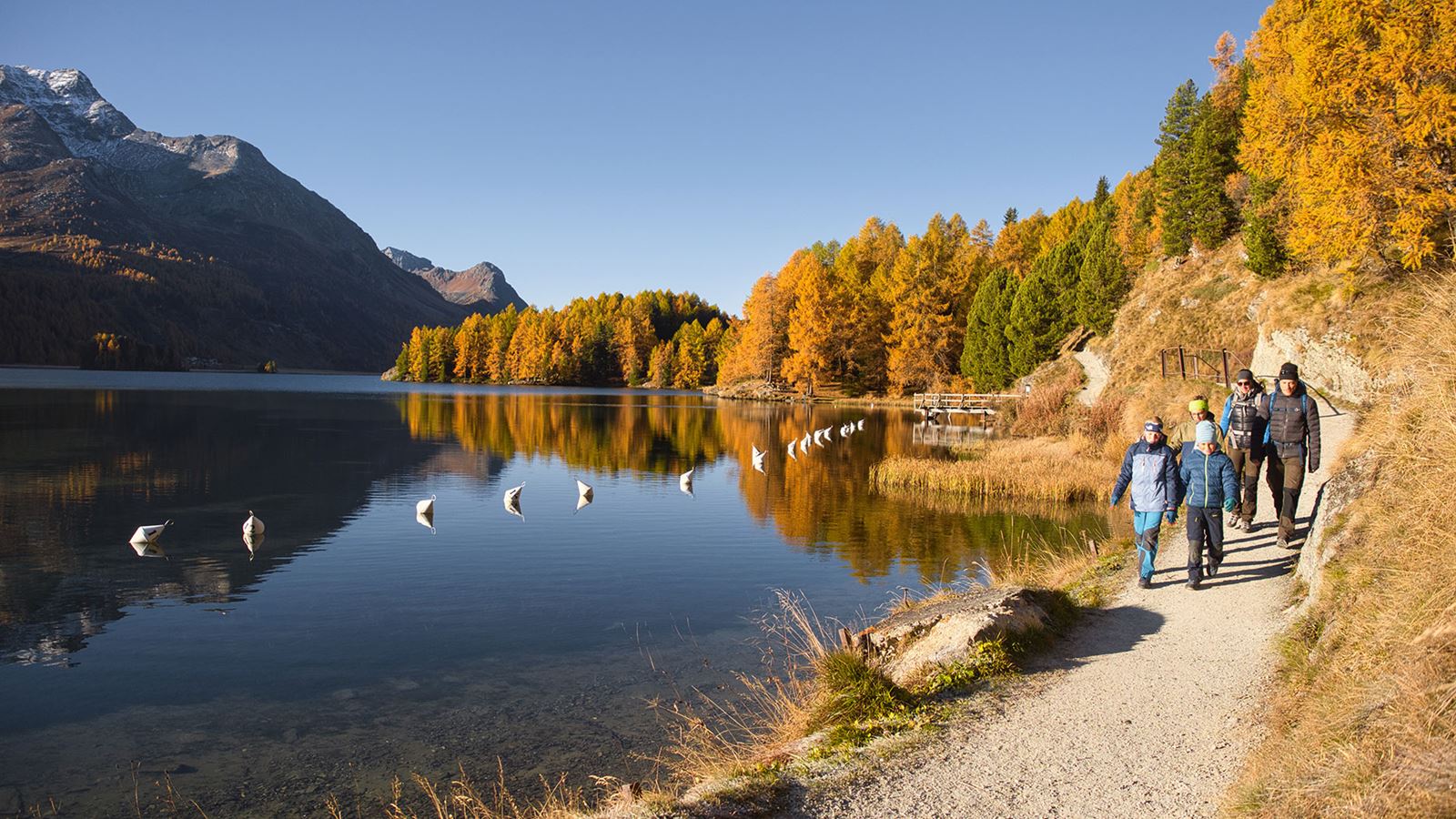 A family hikes along a mountain lake for a pleasant autumn day.