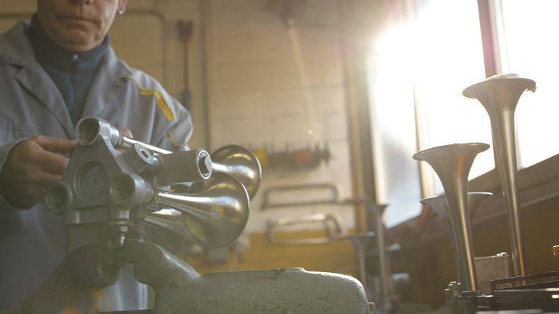 A man restoring a post horn in a workshop.