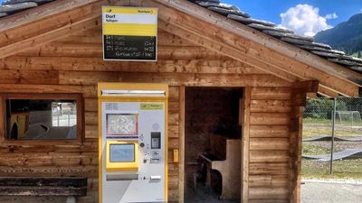 PostBus wooden shelters. Inside is a brown piano with a chair